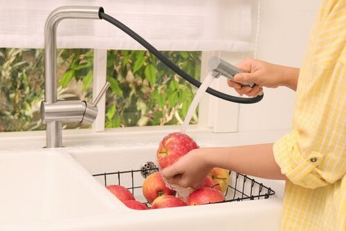 אישה שוטפת תפוחים בעזרת ברז למטבח נשלף
